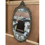 AN OVAL SHAPED GILT FRAMED ORNATE MIRROR