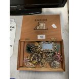 A WOODEN BOX OF ASSORTED COSTUME JEWELLERY AND BADGES ETC