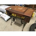 A VINTAGE SINGER SEWING MACHINE IN AN OAK CABINET WITH CAST IRON SUPPORTS AND TREDDLE