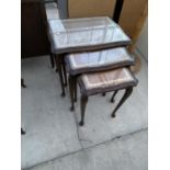 A MAHOGANY NEST OF TABLES WITH LEATHER AND GLASS TOPS