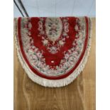 AN OVAL RED PATTERNED RUG