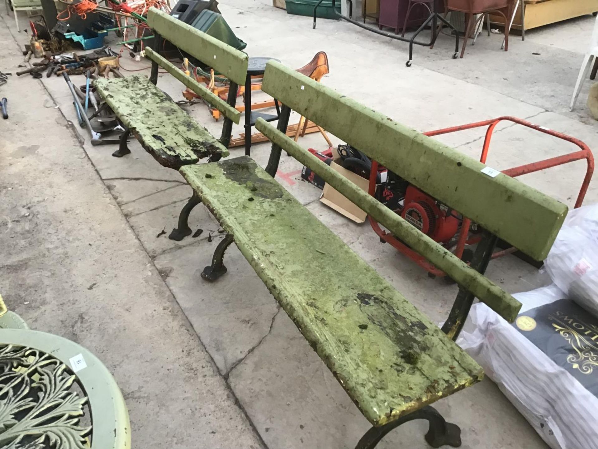 TWO WOODEN BENCHES ON CAST IRON SUPPORTS IN NEED OF RESTORATION