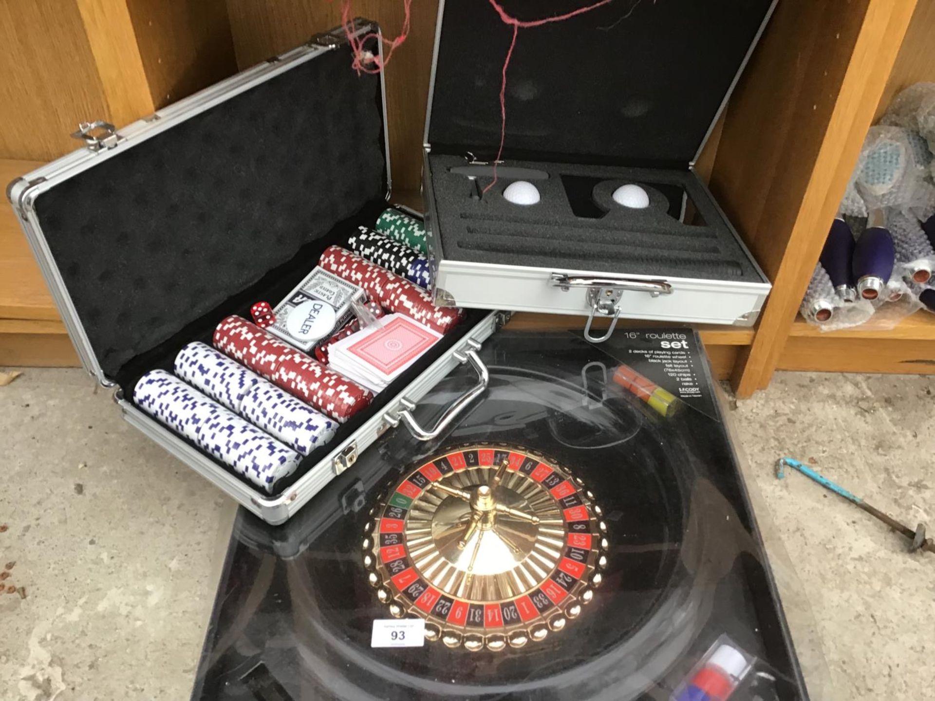 A METAL LOCKABLE CASE WITH KEYS CONTAINING A GOLF KIT, AN AS NEW CASED POKER KIT AND A ROULETTE SET