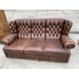 A BROWN LEATHER WING AND BUTTON BACK CHESTERFIELD THREE SEATER SOFA