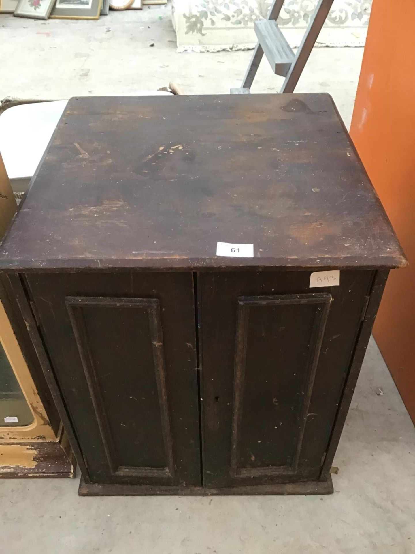 A SMALL WOODEN TWO DOOR CABINET