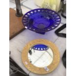 A BLUE GLASS FRUIT BOWL AND AN ORNATE FRAMED CIRCULAR MIRROR