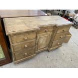 A RUSTIC PINE SIDEBOARD WITH ONE DOOR AND SEVEN DRAWERS