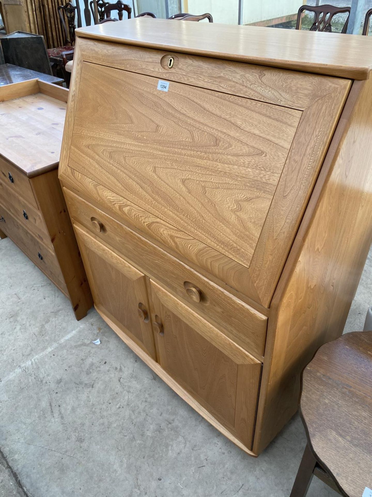 AN ERCOL GOLDEN DAWN WINDSOR BUREAU WITH FALL FRONT, TWO DOORS AND ONE DRAWER