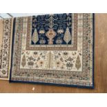 A LARGE BLUE AND CREAM PATTERNED RUG