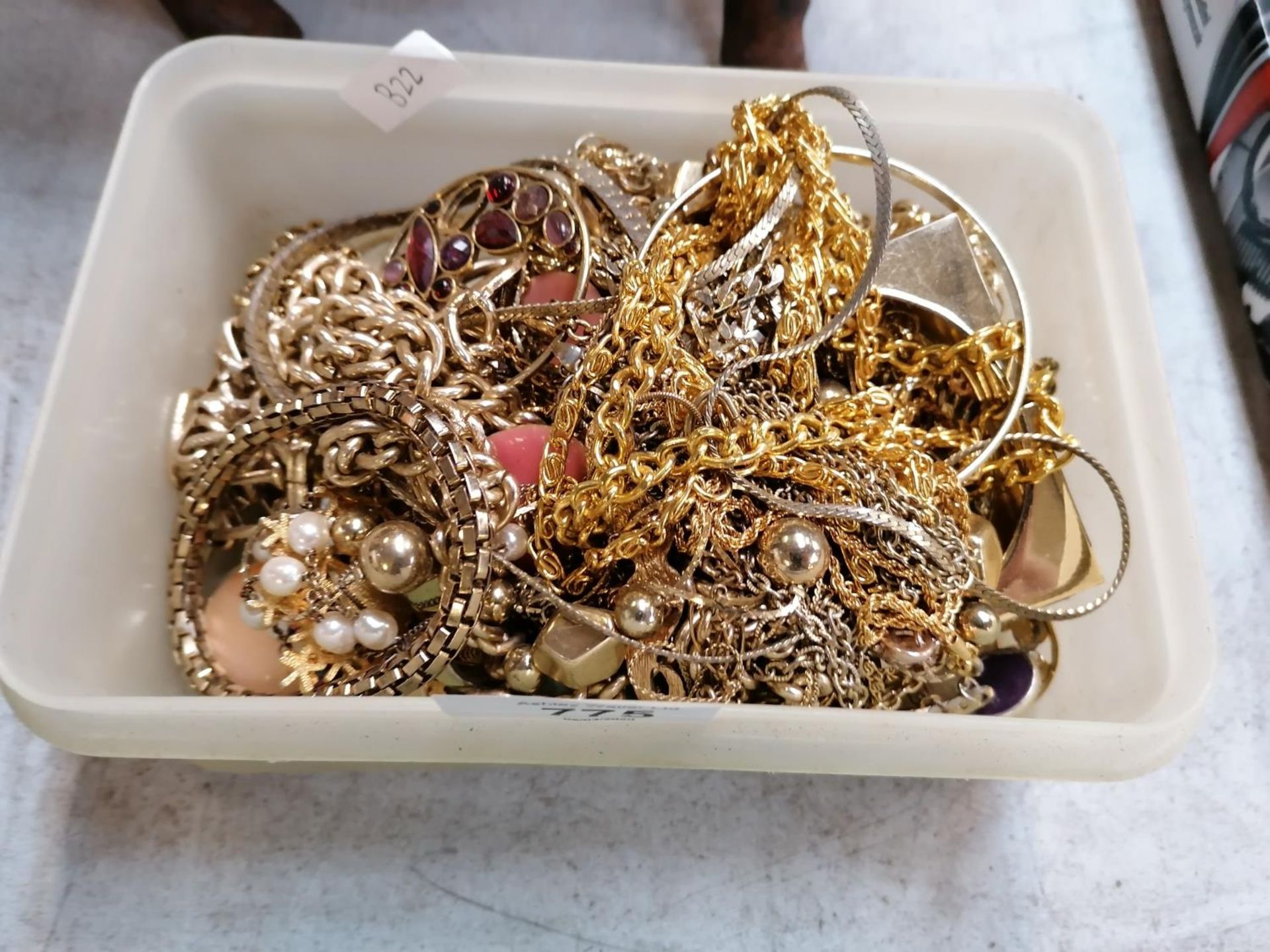 A TUB OF YELLOW METAL COSTUME JEWELLERY