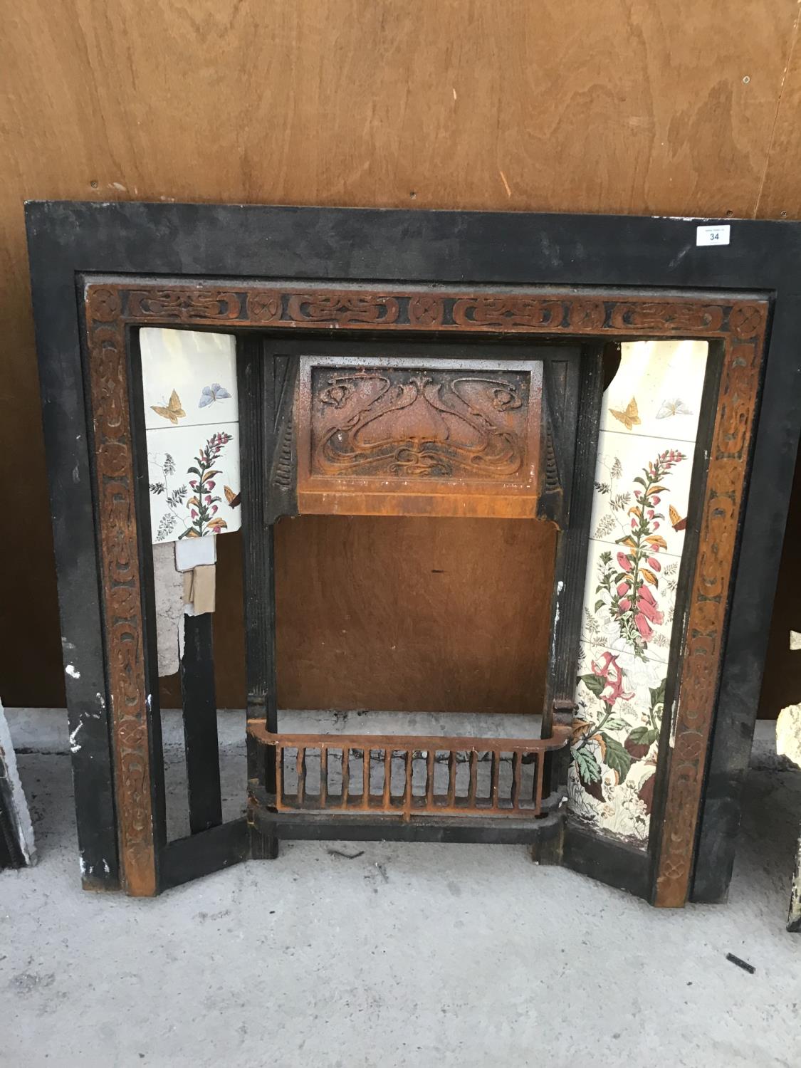 AN ORNATE CAST IRON FIR PLACE WITH TILED SIDES (TILES DAMAGED)