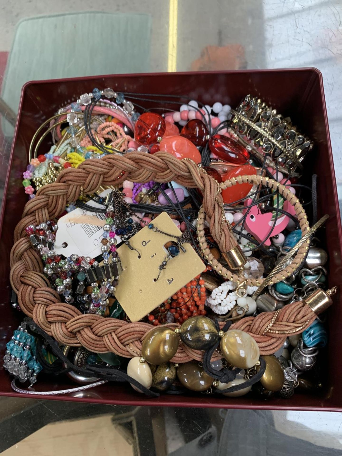 A METAL TIN CONTAINING ASSORTED COSTUME JEWELLERY