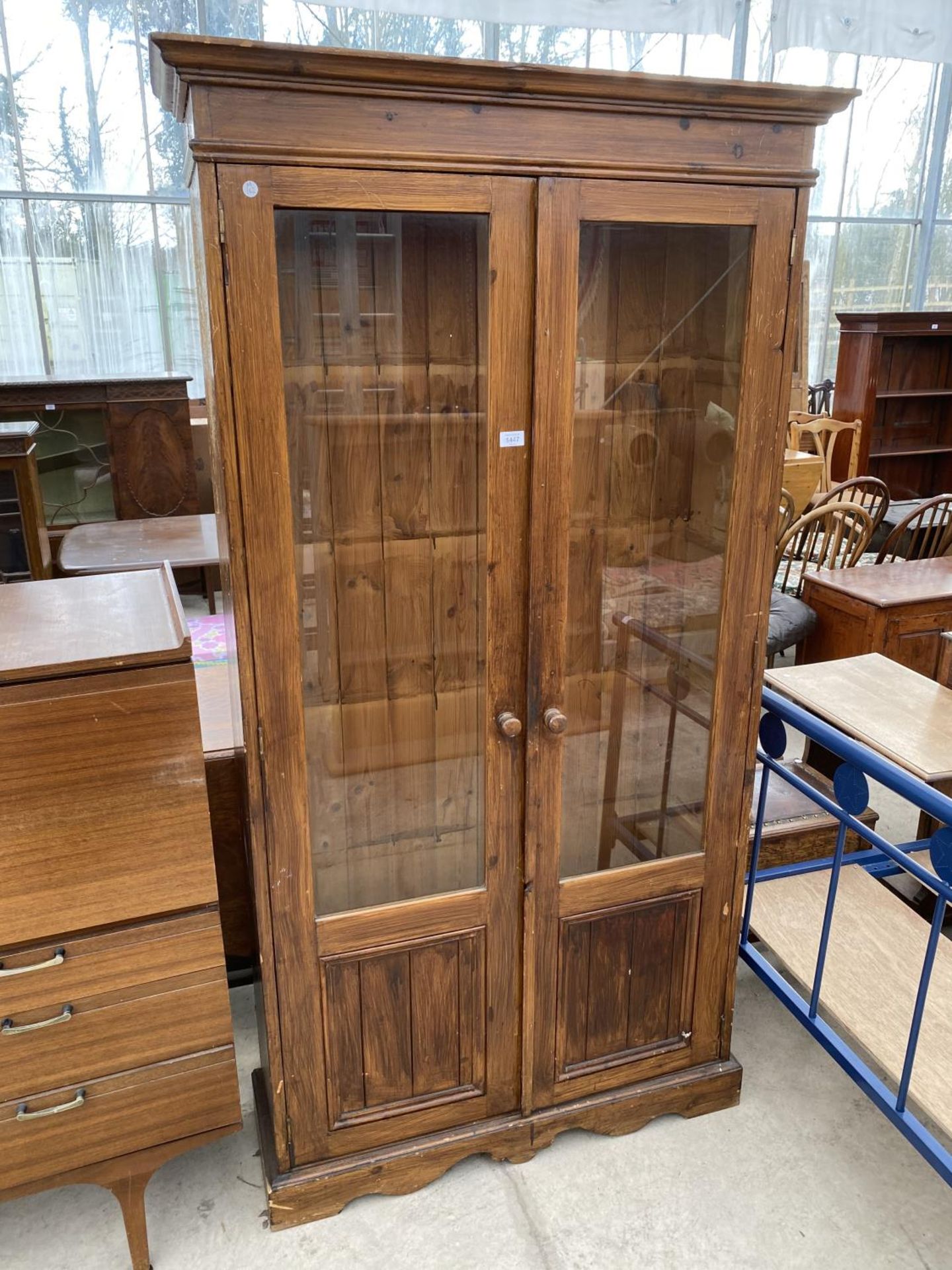 A TALL PINE CABINET WITH TWO GLAZED DOORS