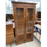A TALL PINE CABINET WITH TWO GLAZED DOORS