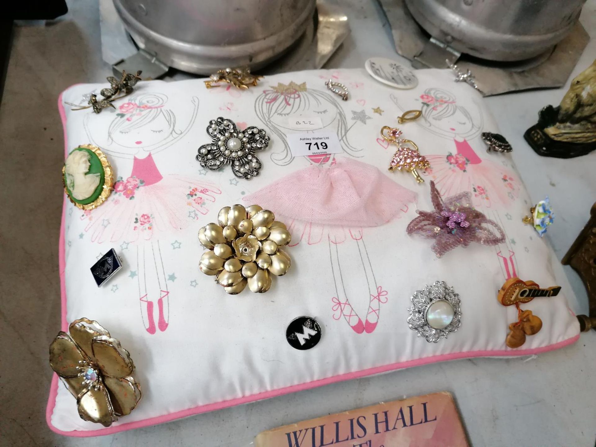 A CUSHION OF ASSORTED COSTUME JEWELLERY BROOCHES