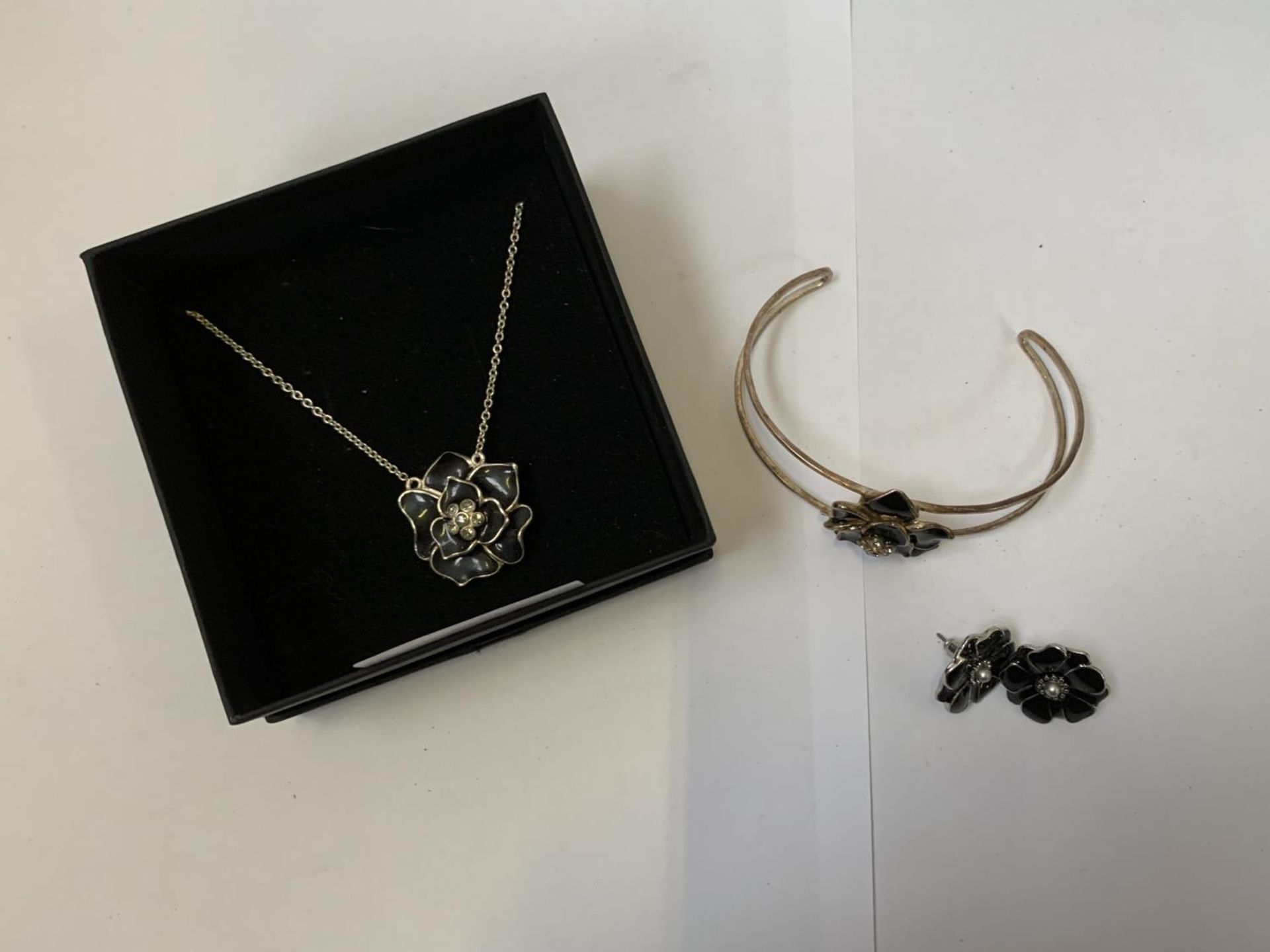 A SILVER NECKLACE, BRACELET AND EARRINGS SET WITH BLACK FLOWER DESIGNS