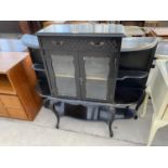 A VICTORIAN EBONISED CREDENZA ON CABRIOLE SUPPORTS WITH TWO GLAZED DOORS, ONE DRAWER AND SIDE