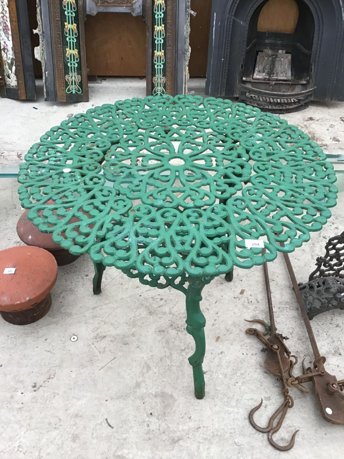 A GREEN PAINTED ORNATE CAST IRON GARDEN TABLE WITH LOWER SHELF