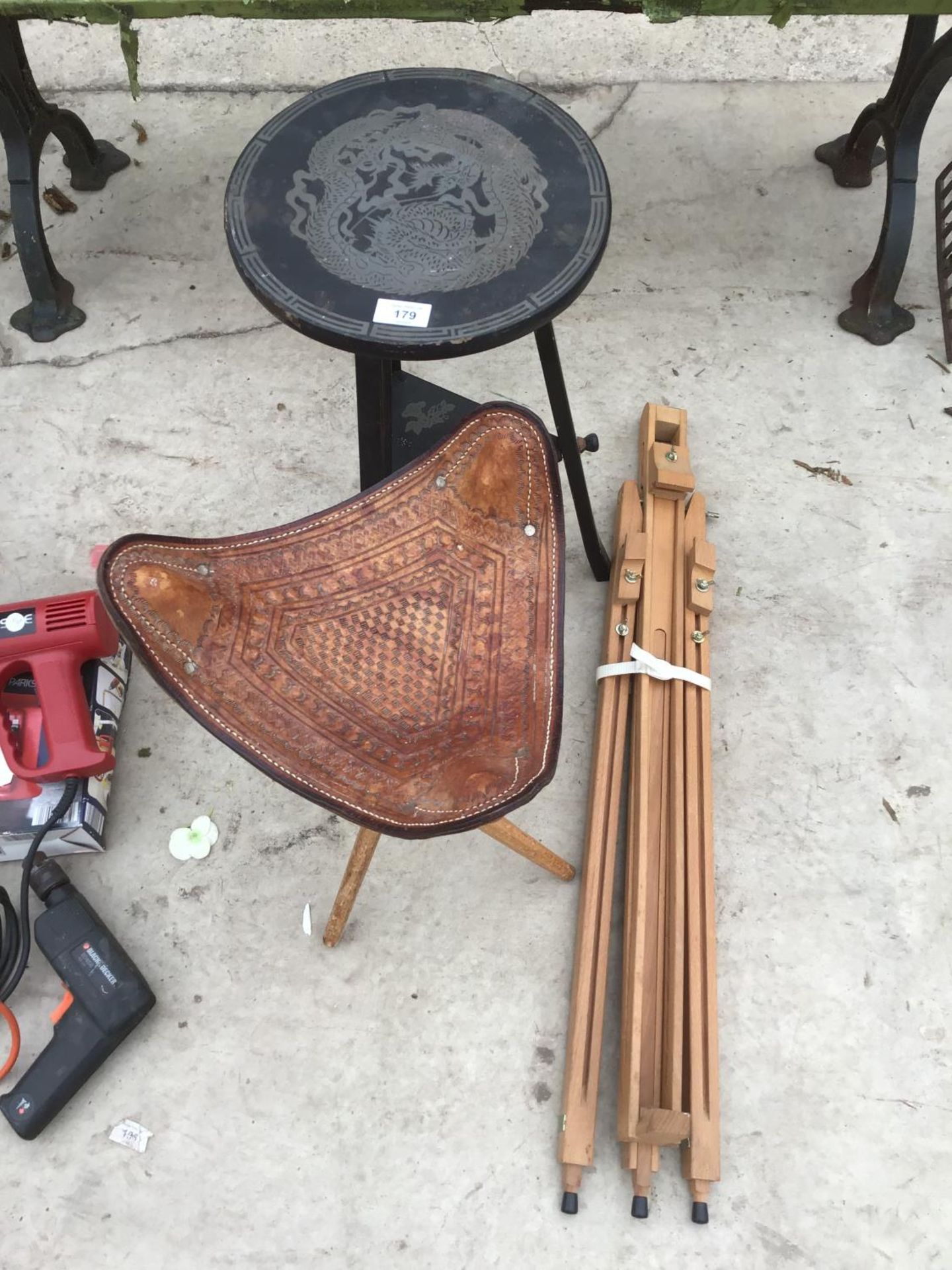 A LEATHER TOPPED THREE LEGGED FOLDING STOOL, AN EASEL AND A WOODEN CHINESE STYLE TABLE WITH LOWER