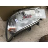 A NEW AND BOXED FRONT LIGHT UNIT FOR A MERCEDES SPRINTER VAN AND SOME BADGES