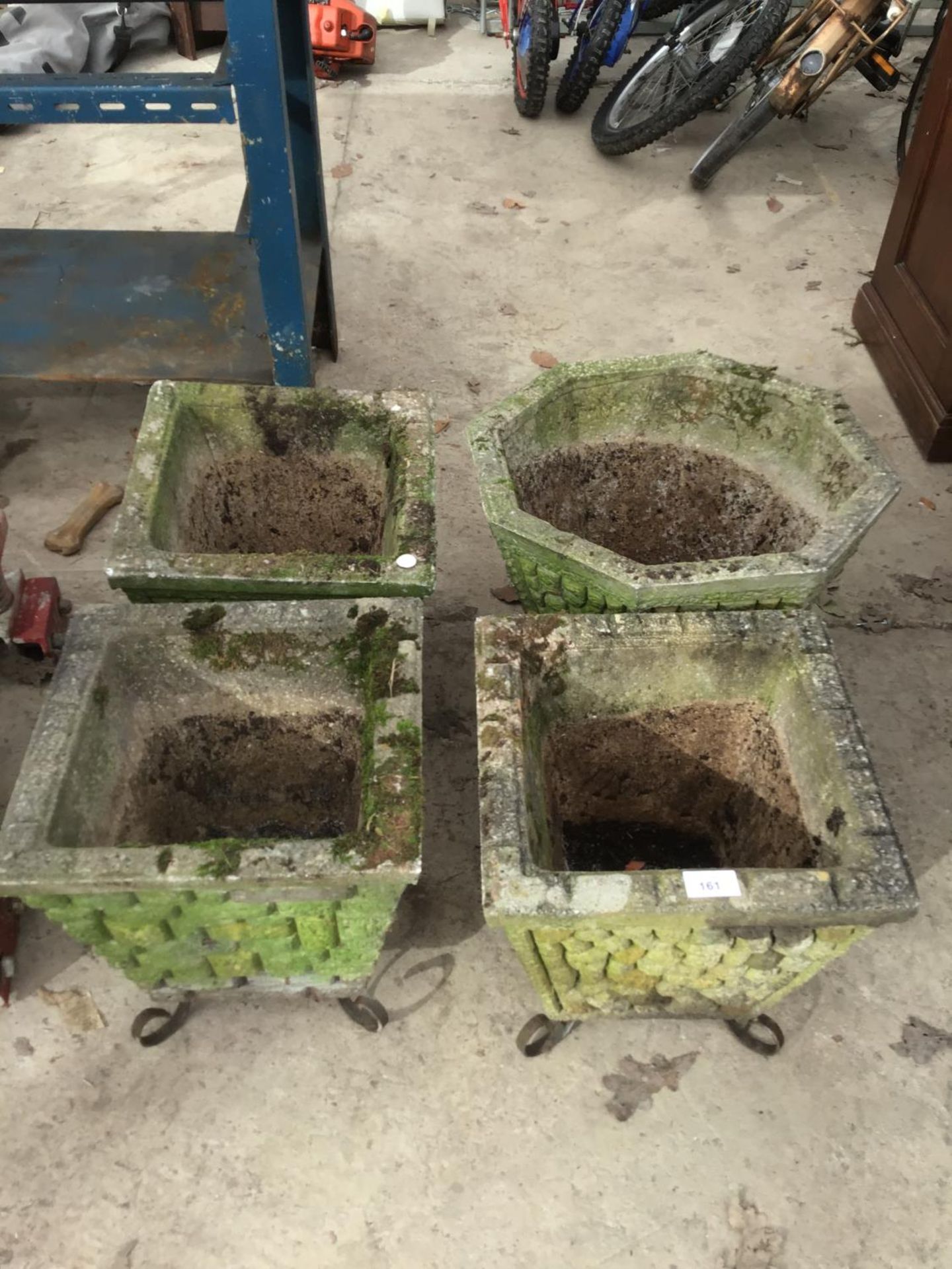 FOUR CONCRETE PLANTERS ON WROUGHT IRON LEGS