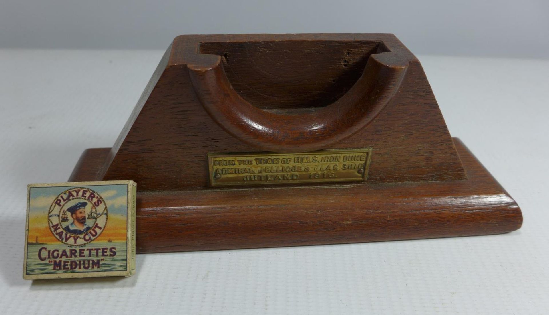 A WATCH HOLDER FROM THE TEAK OF H.M.S IRON DUKE AND A MINIATURE PLAYERS CIGARETTE PACKET