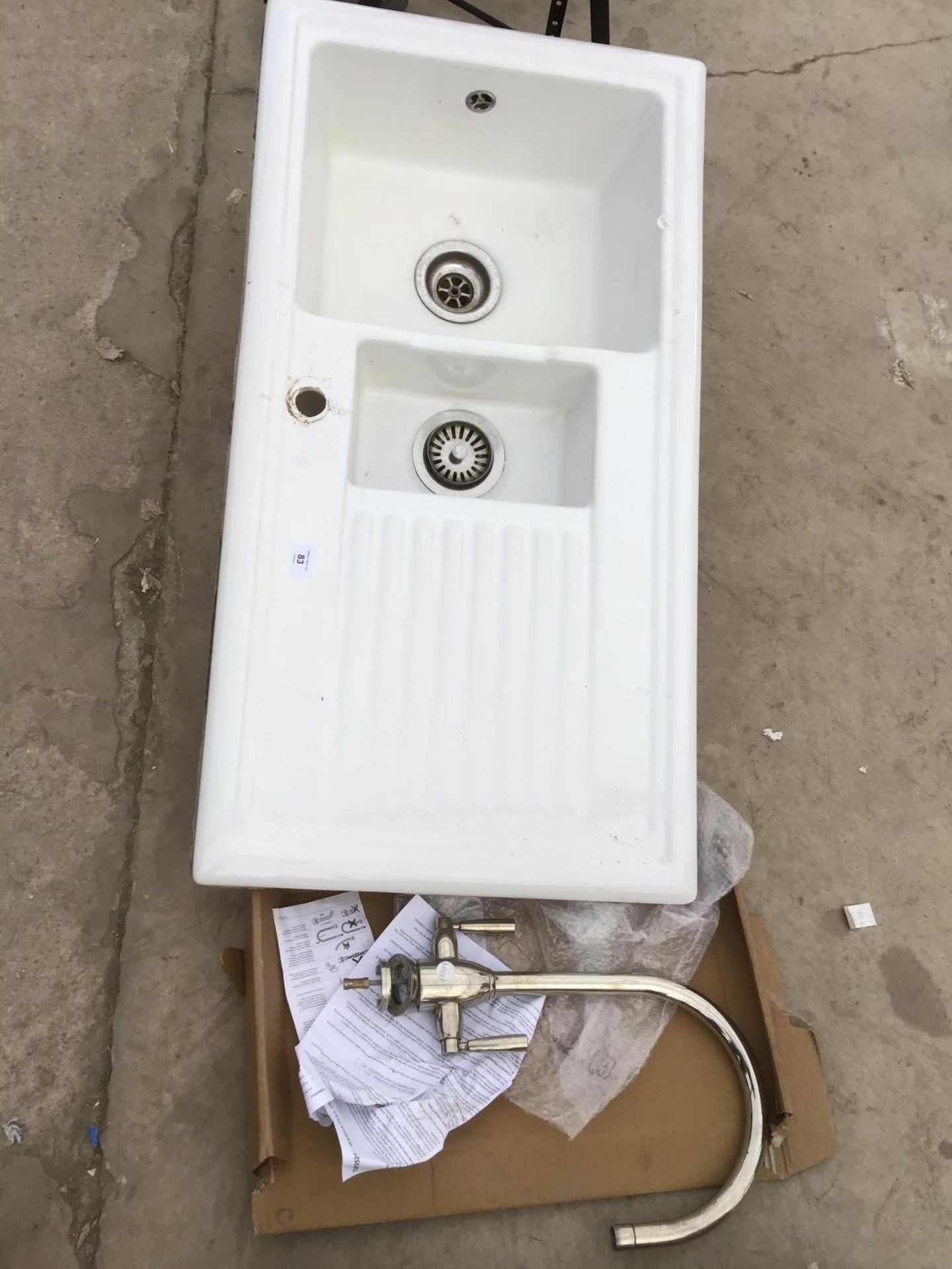 A WHITE SINK WITH DOUBLE BOWLS, A CHROME MIXER TAP AND A CHROME BATH MIXER TAP WITH SHOWER HEAD