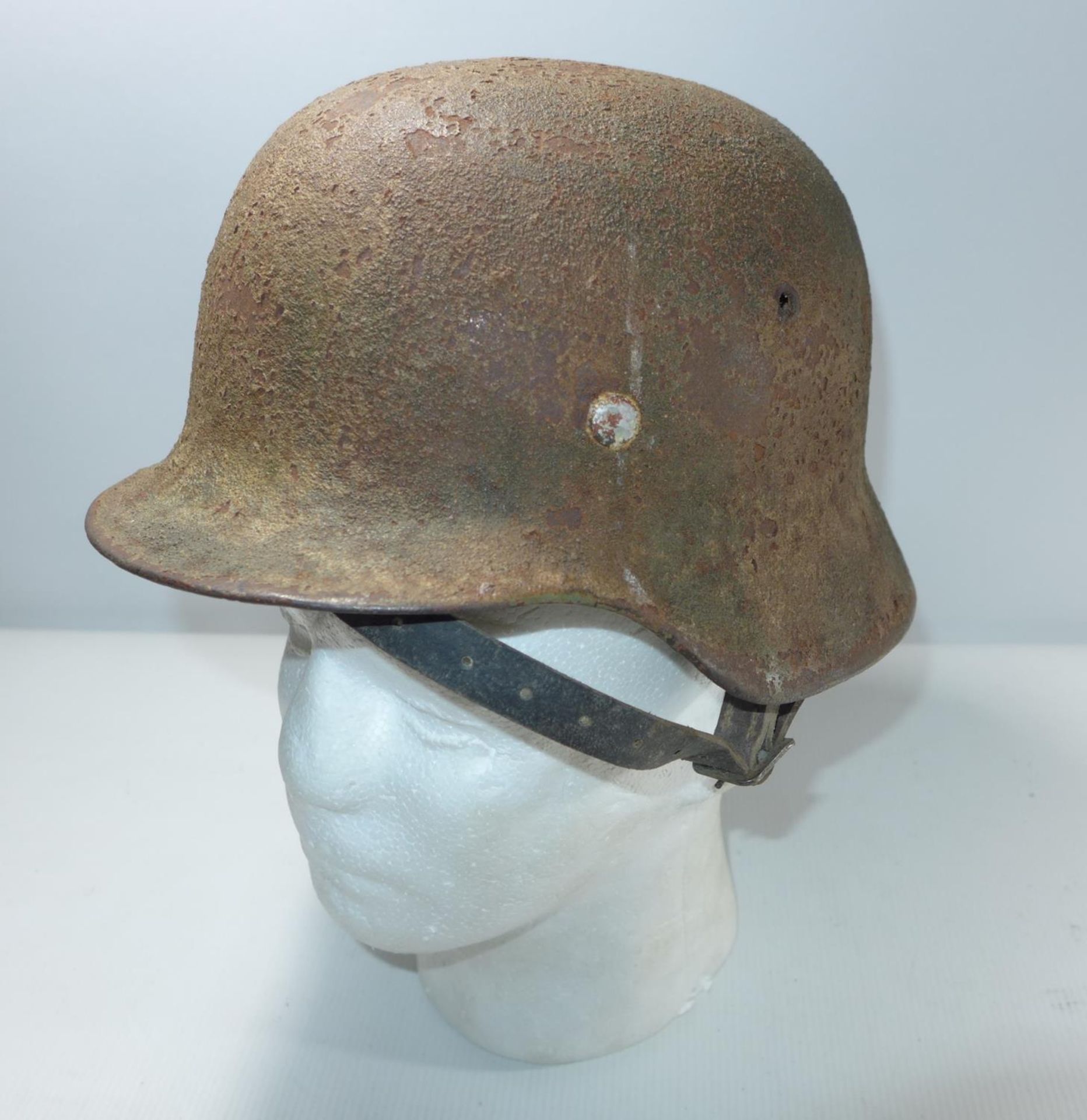 A GERMAN RUSTED AND GREEN PAINTED HELMET