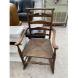 AN OAK LADDER BACK ROCKING CHAIR WITH RUSH SEAT