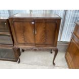 A MAHOGANY COCKTAIL CABINET ON CARVED CABRIOLE SUPPORTS WITH TWO DOORS