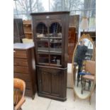 A JAYCEE OAK CORNER CABINET WITH LOWER DOOR AND UPPER GLAZED PANEL DOOR