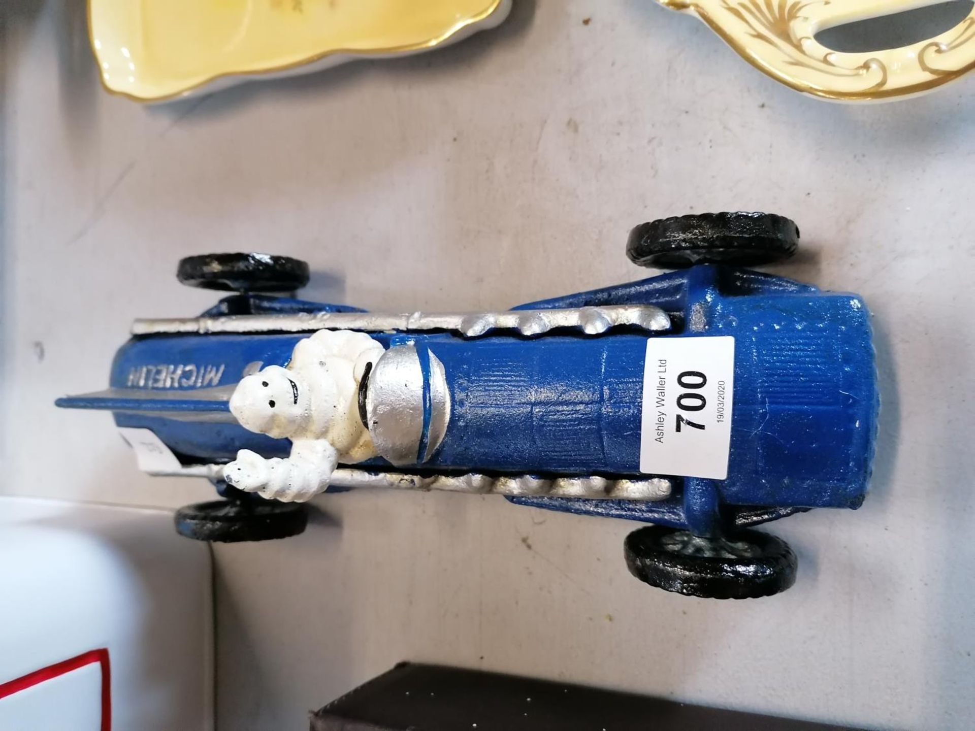 A MICHELIN MAN IN A CAST BLUE RACING CAR