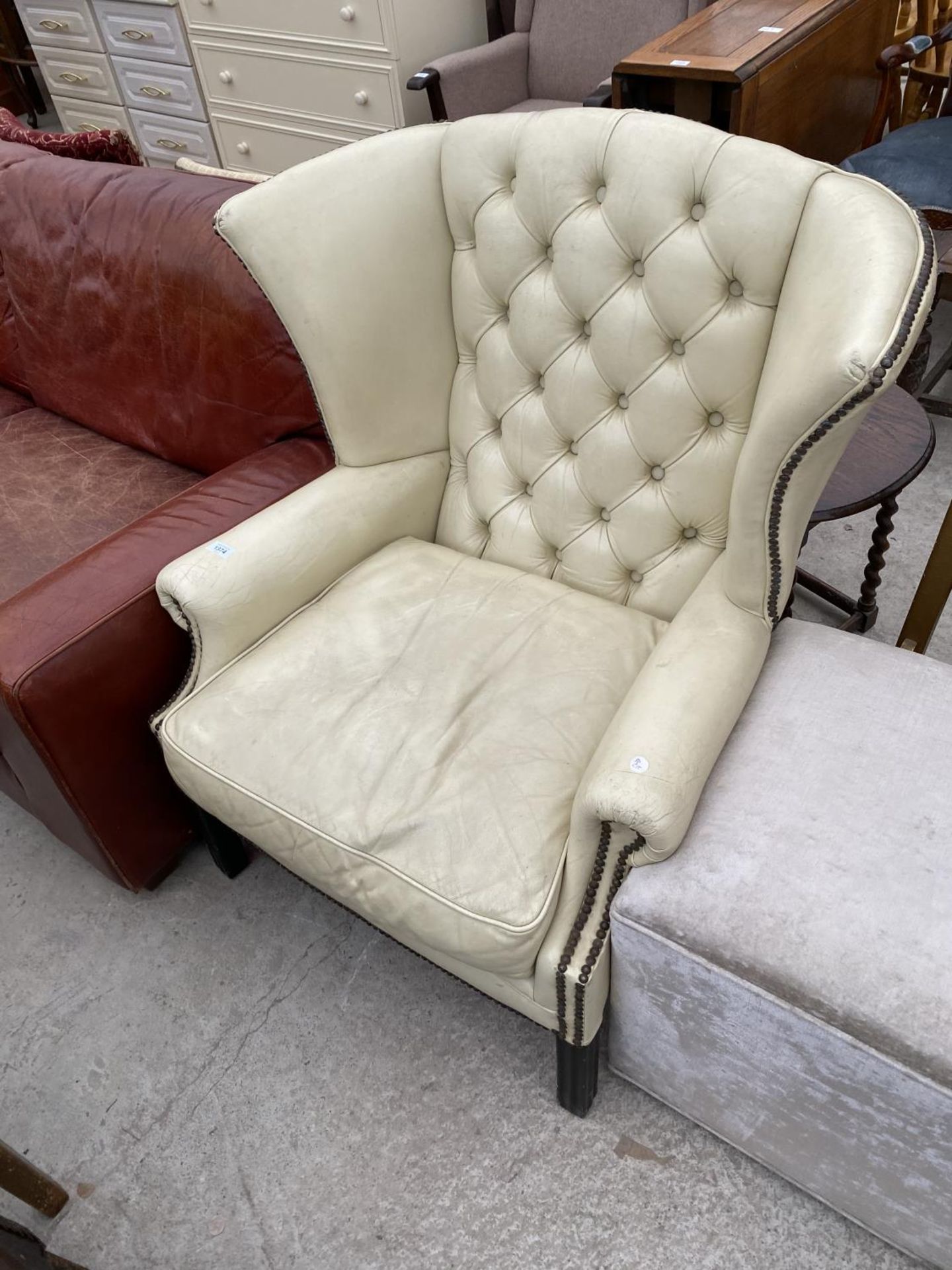 A STUDDED CREAM LEATHER WING AND BUTTON BACK ARMCHAIR