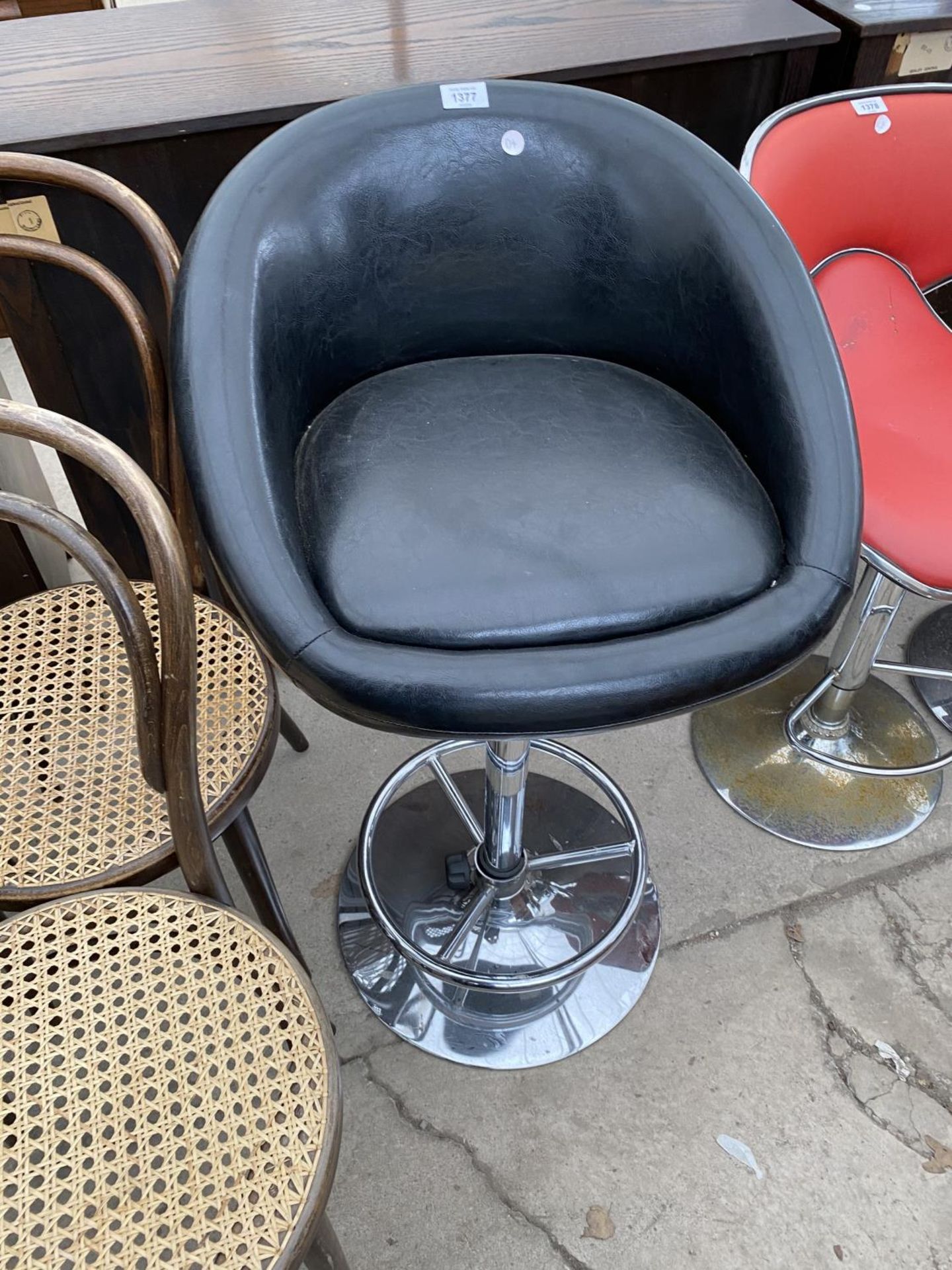 A BLACK BAR STOOL ON CHROME SWIVEL SUPPORT