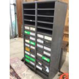 A TALL METAL STORAGE UNIT WITH THIRTY FOUR SMALL DRAWERS AND ELEVEN PIGEON HOLES