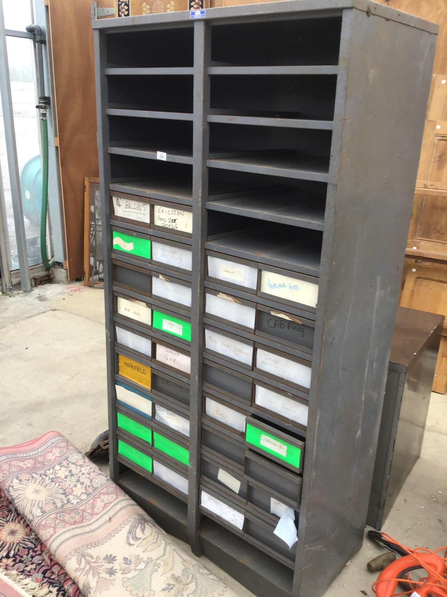 A TALL METAL STORAGE UNIT WITH THIRTY FOUR SMALL DRAWERS AND ELEVEN PIGEON HOLES