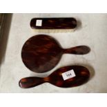 A TORTOISHELL EFFECT THREE PIECE DRESSING TABLE SET COMPRSING OF A MIRROR AND TWO BRUSHES