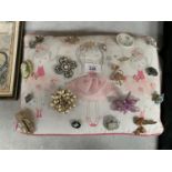 A BALLERINA CUSHION OF ASSORTED COSTUME JEWELLERY BROOCHES TO INCLUDE DIAMANTE, CAMEO, PEARL