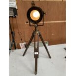 A STAGE LIGHT ON A WOODEN TRIPOD IN WORKING ORDER