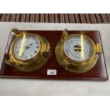 A BRASS CASED BAROMETER AND CLOCK ON A WOODEN PLINTH