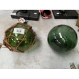 A PAIR OF GREEN GLASS BALLS ONE WITH ROPE