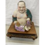 A LARGE CHINESE POTTERY MODEL OF A SEATED BUDDHA ON CARVED WOODEN DISPLAY STAND, MARKS TO BASE,