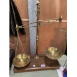 A VINTAGE SET OF BRASS SCALES ON A WOODEN BASE