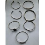 SEVEN MARKED SILVER BANGLES TO INCLUDE A DOLPHIN DESIGN, TEARDROP, SWIRL ETC