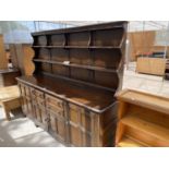 A LARGE ERCOL ELM DRESSER WITH FOUR DOORS, FOUR DRAWERS AND UPPER PLATE RACK