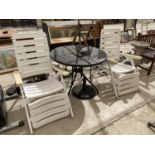 A BLACK CIRCULAR GARDEN TABLE WITH PARASOL BASE AND TWO WHITE RECLINER CHAIRS