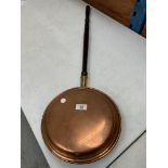 A BRASS WARMING PAN WITH WOODEN HANDLE