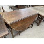 AN OVAL OAK DROP LEAF DINING TABLE ON BARLEY TWIST SUPPORTS