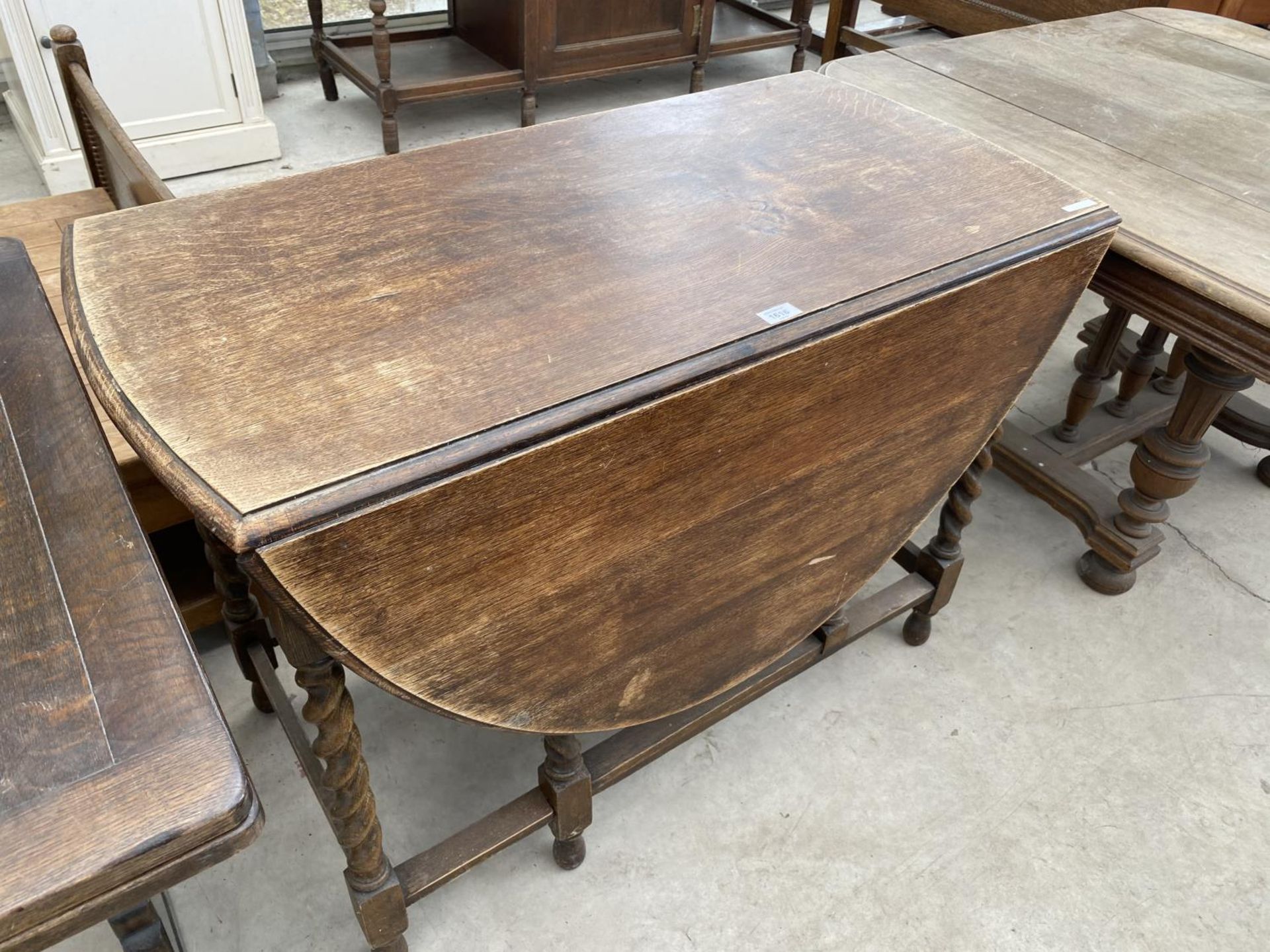 AN OVAL OAK DROP LEAF DINING TABLE ON BARLEY TWIST SUPPORTS