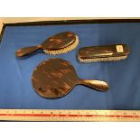 A TORTOISHELL EFFECT THREE PIECE DRESSING TABLE SET COMPRSING OF A MIRROR AND TWO BRUSHES